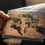 Tyler holding a photo of himself in uniform