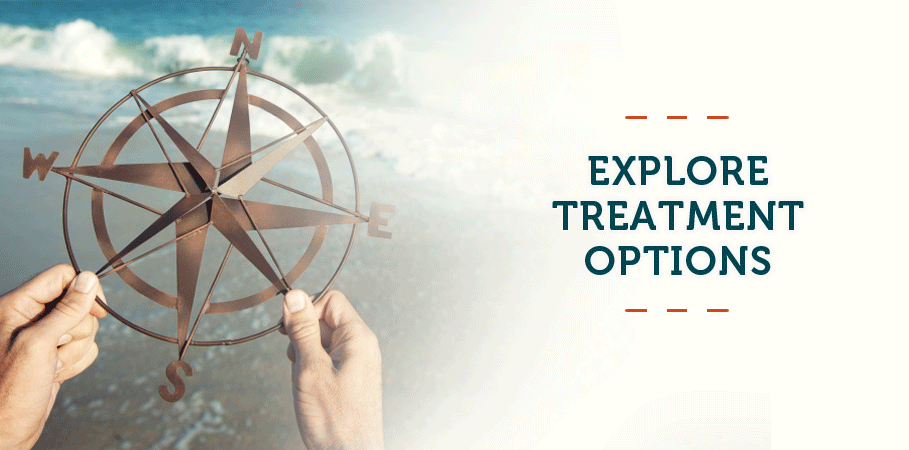 Hands holding large compass along the shoreline.