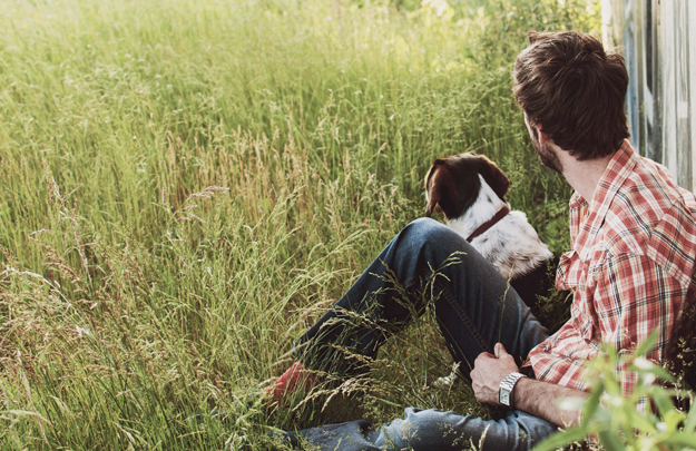 Man with dog sitting in field